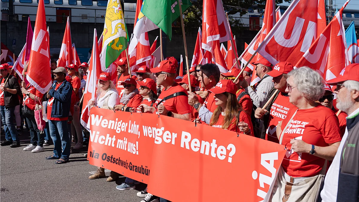 Menschen in roten Unia-Shirts demonstrieren mit Fahnen und Transparenten für bessere Löhne und Renten.